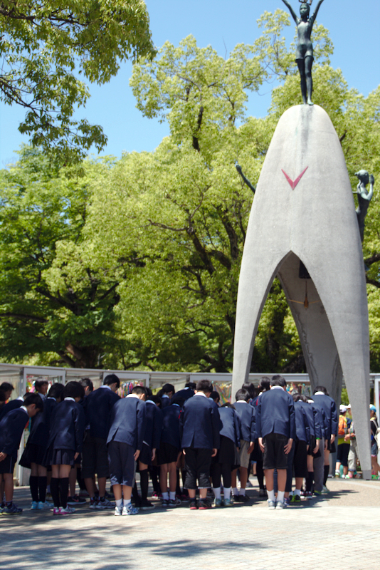 grupo de niños saludando delante del Monumento a la Paz de los niños en el Parque de la Paz de Hiroshima