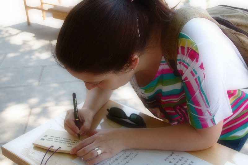 Lidia escribiendo en una tablilla ema el en Santuario Meiji de Harajuku en Tokio